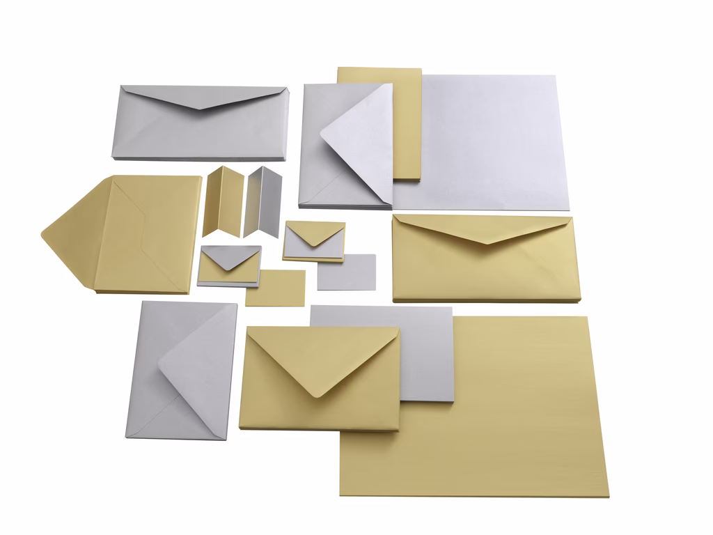 Sammlung von Umschlägen und Briefpapier in Creme und Grau auf weißem Hintergrund.